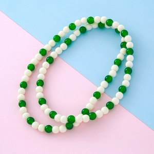 Collier élégant avec perles vertes style jade et blanches mates sur fond pastel bicolore