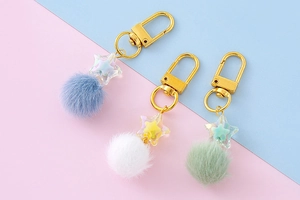 Close-up of star pompom keychains with golden metal clasps in pastel candy colors