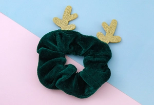 Nahaufnahme eines dunkelgrünen Samt-Scrunchies mit glitzernden goldenen Rentiergeweihen