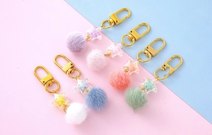 Flat lay of colorful star pendants with plush pom-poms and golden lobster clasps