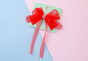 Détail d'un nœud en tulle rouge avec des rubans à carreaux rouges et blancs sur carte