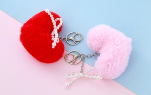 Detail view of plush heart keychains with pearls and bows on a pastel background