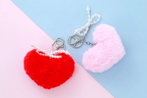 Close-up of red and pink plush heart charms with pearl bow and golden keychains