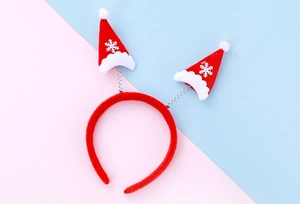 Détail d'un serre-tête de Noël en velours rouge avec mini bonnets de Père Noël à ressorts