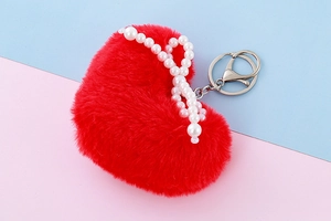 Detailed close-up of a red plush heart pendant with pearl bow and silver lobster clasp