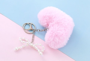 Detailed shot of plush pink heart keychain with faux pearl bow and silver clasp
