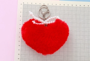 Close-up of red plush heart keychain with faux pearl bow and silver lobster clasp