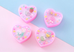 Detailansicht von vier herzförmigen rosa Geschenkboxen mit buntem Perlenschmuck für Kinder