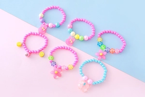 Détail de bracelets perlés pour enfants avec pendentifs en résine mignons et fini nacré