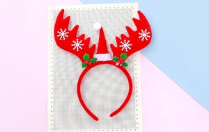 Détail du serre-tête de Noël rouge avec des bois de renne et un petit bonnet de Noël
