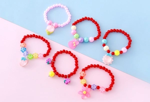 Détail de bracelets perlés pour enfants avec breloques en résine de fruits et lapin