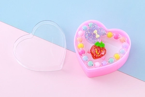Nahaufnahme von Kinder-Schmuckset mit Perlenarmband und Erdbeerring in einer Herzbox