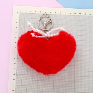 Red plush heart keychain with white faux pearls and silver clasp on a scale mat