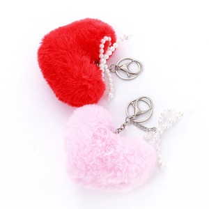 Red and pink plush heart keychains with pearl bows and silver metal clips on white background