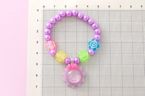 Détail d'un bracelet de perles violettes avec perles fleurs souriantes et pendentif soleil