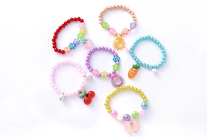 Détail de bracelets en perles de résine colorées avec des breloques de fruits et fleurs