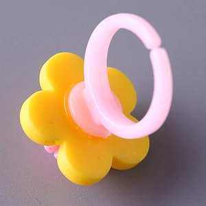 Gelber Blumen-Acrylring für Kinder mit rosa verstellbarem Band auf grauem Grund