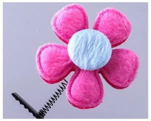 Détail de la pince à cheveux fleur en peluche rose avec centre bleu sur ressort métal