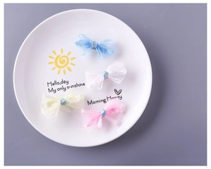 Detail of four colorful tulle lace bow hair clips in pastel shades on a white plate