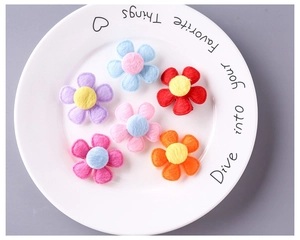 Close-up of colorful plush five-petal flower hair clips for kids on a white ceramic plate