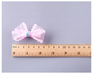 Detailed view of a pink mesh bow hair clip measuring approximately 6cm on a wooden ruler