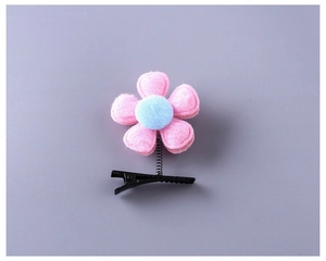 Détail d'une barrette à fleurs en feutre rose avec centre bleu sur un clip bec de canard
