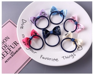 Set of 6 colorful candy-colored bow hair ties with cute cartoon prints in a white dish