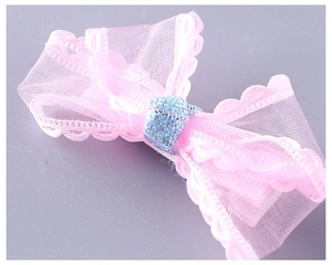 Detail of pink mesh bow hair clip with scalloped edges and blue glitter center ribbon