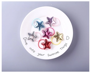 Close-up of colorful PU star hair ties and elastic bands for girls in a white plate