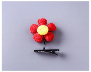 Détail d'une pince à cheveux fleur rouge en peluche avec ressort et centre jaune vif