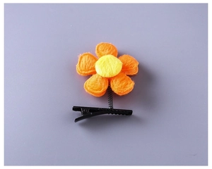 Détail d'une pince à cheveux fleur en peluche orange avec ressort et clip crocodile