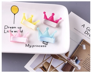 Détail de quatre barrettes couronne en tissu coloré pour filles sur plateau céramique
