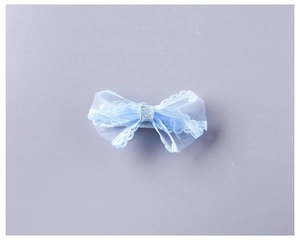 Close-up detail of light blue lace bow hair clip with translucent mesh and silver glitter center