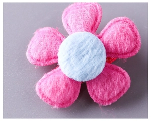 Macro detail of a soft plush pink five-petal flower hair clip with a blue center core