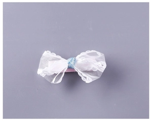 Detail of children's white lace mesh bow hair clip with blue glitter center and wavy edges