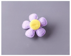Close-up of handmade purple felt flower hair clip with yellow center and stitching details