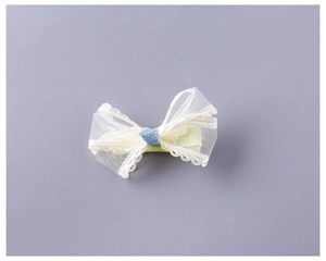 Close-up of yellow lace bow hair clip with blue glitter center and mesh texture detail