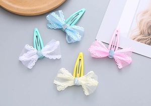Detail of four colorful lace mesh bow hair clips in blue white pink and yellow