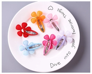 Detail of colorful fabric-wrapped floral BB hair clips for girls in a white ceramic dish