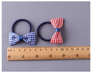 Macro detail of 4.5cm gingham bow hair tie set with a wooden ruler for scale