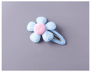 Close-up of plush blue flower hair clip with soft pink center and fabric wrap