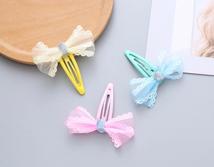Close-up of three colorful mesh lace bow hair clips for girls on a wooden tray