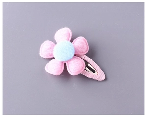 Detailed close-up of pink felt flower hair clip with light blue center and fabric wrap