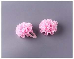 Dettaglio di due fermagli per capelli a fiore in nastro rosa arricciato per bimbe