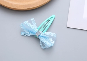Close-up of blue lace mesh bow hair clip with wavy embroidery and silver center