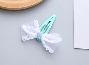 Detailed macro view of mint green metal hair clip with white lace mesh bow for girls