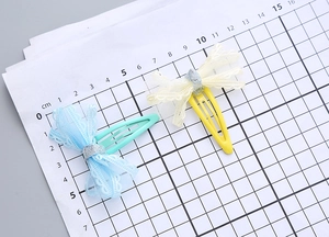 Detail of handmade lace mesh bow hair clips in light blue and yellow with glitter center