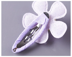 Close-up of purple ribbon wrapped BB clip with white mesh flower petals for children