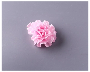 Dettaglio di un fermaglio a fiore in nastro rosa con base a becco d'anatra bianca