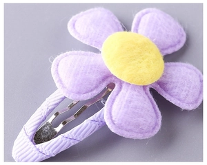 Macro detail of purple fabric flower BB hair clip with yellow center and ribbon wrap